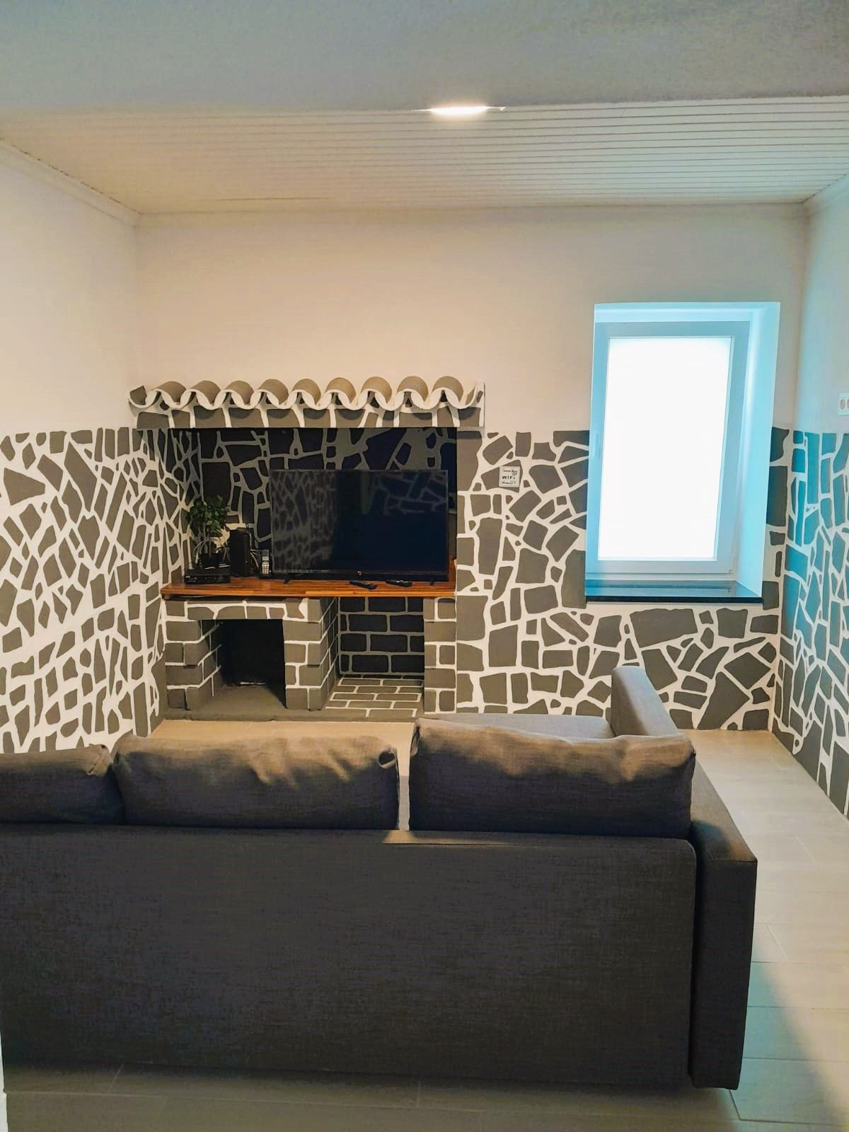 Sala de estar com sofá e parede em pedra