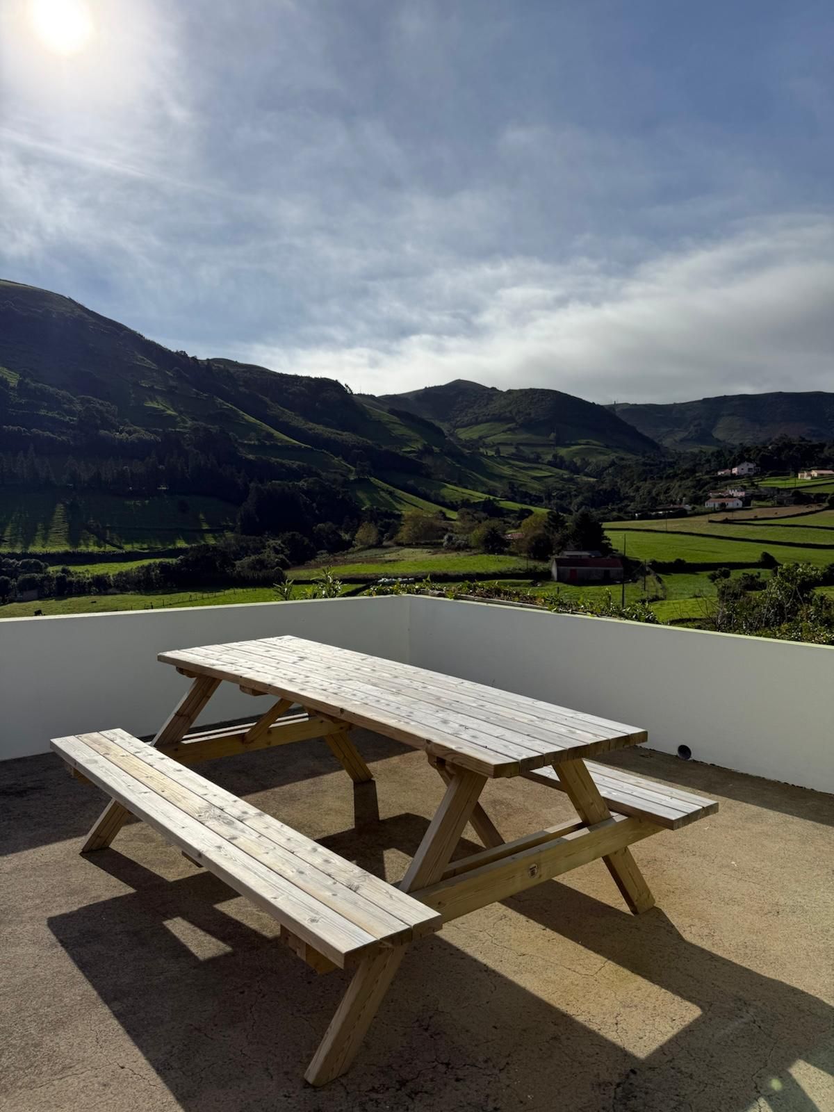 Mesa de piquenique no terraço, com o vale e as encostas ao fundo